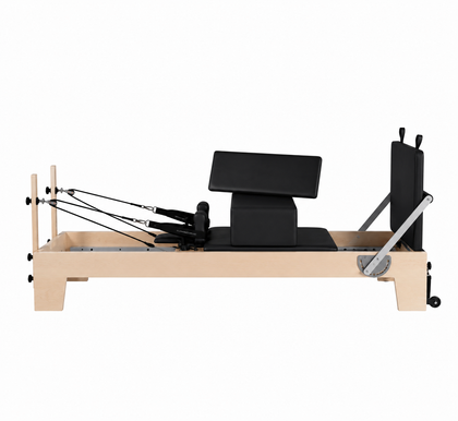 REFORMIA Maple Wood Pilates Reformer with Black upholstery and solid maple frame, three-quarter studio view